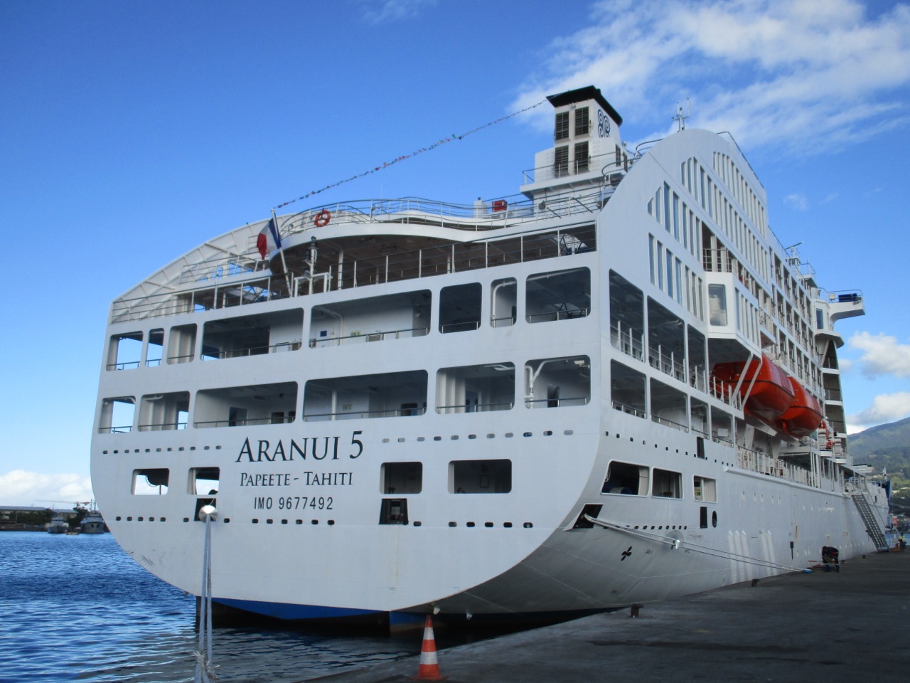 Poupe de l'Aranui 5 amarré au quai de Papeete sous un ciel bleu