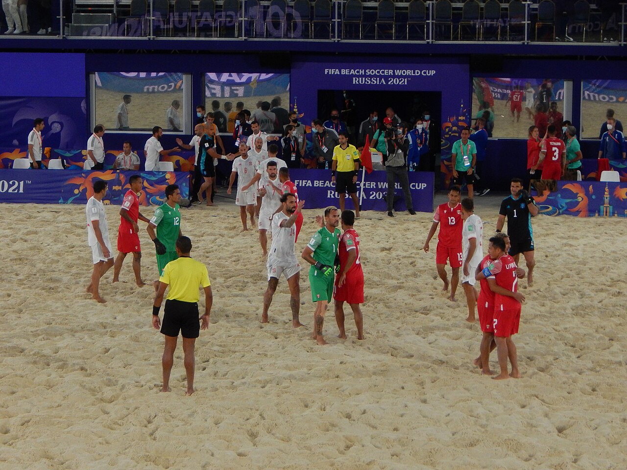 Joueurs de Tahiti en rouge et d'Espagne en blanc se saluant sur le sable à la fin d'un match de Coupe du monde de beach soccer