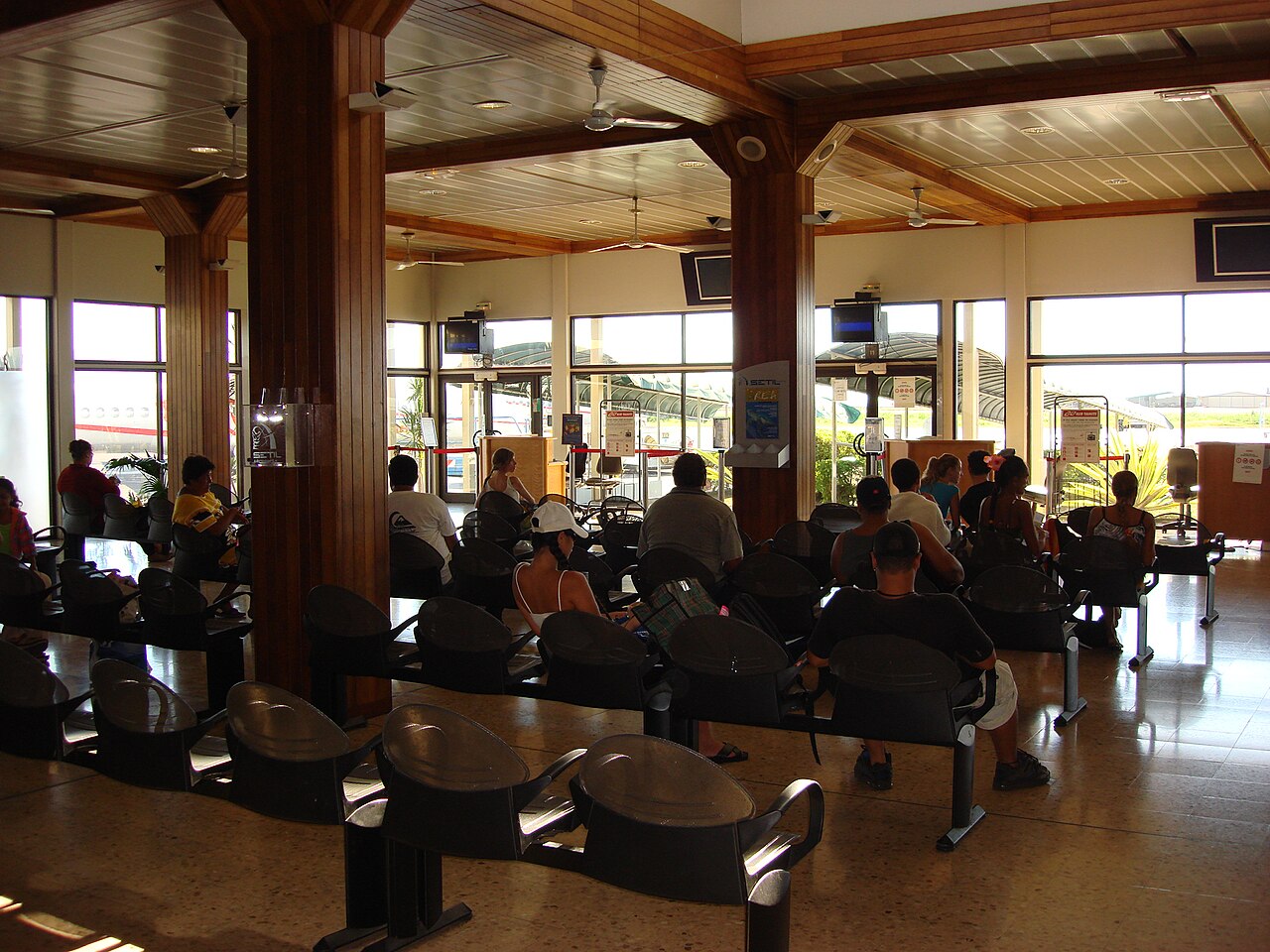 Salle d'attente de l'aérogare de Tahiti-Faa'a avec ses poutres en bois et ses sièges alignés