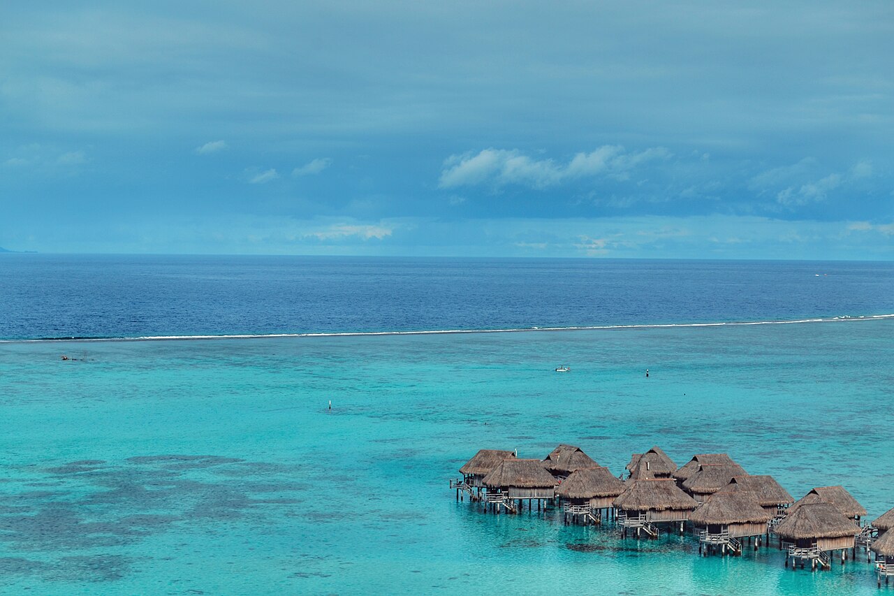 Bungalows sur pilotis au-dessus du lagon turquoise de Moorea, avec la barrière de corail au fond