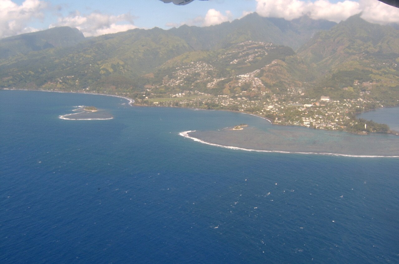Vue aérienne de la côte de Tahiti : lagon bleu, récifs et montagnes verdoyantes à l'arrière-plan